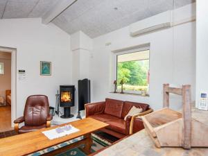 a living room with a couch and a table and a fireplace at Three-Bedroom Holiday home in Aabenraa 1 in Loddenhøj