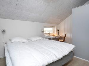 a bedroom with a large white bed and a desk at Holiday home Læsø VII in Læsø