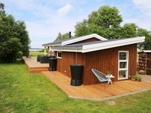 una casa con una terraza de madera con un banco. en Holiday home Jægerspris XXVIII, en Jægerspris