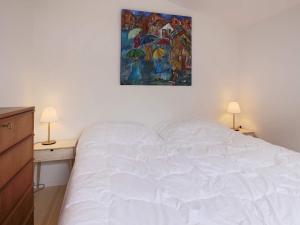 1 cama blanca en una habitación con 2 mesas y un cuadro en Holiday home Jægerspris XXVIII, en Jægerspris