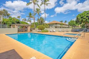 a swimming pool with palm trees and a house at Kihei Bay Surf 236 in Kihei