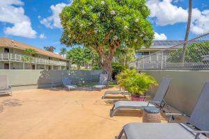 a patio with chairs and a tree in front of a building at Kihei Bay Surf 236 in Kihei