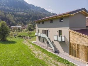 a house with a balcony and a grass yard at Celine Top 3 in Bramberg am Wildkogel