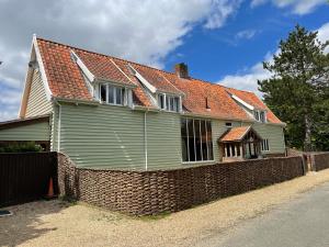 a green house with a brick fence in front of it at Moat Barn in Debach