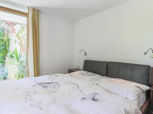 um quarto com uma cama com lençóis brancos e uma janela em Haus Jöchl Top 2 em Sankt Johann in Tirol