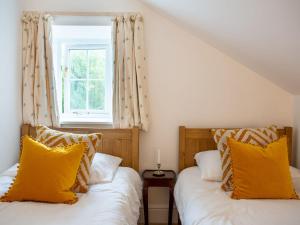 2 Betten mit gelben Kissen in einem Zimmer mit Fenster in der Unterkunft The Bothy in Boltby