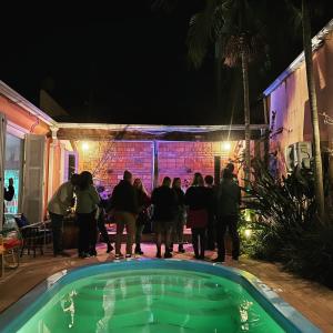 un gruppo di persone che di notte si aggirano intorno a una piscina di Pelotas Bier Hostel a Pelotas