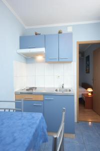 - une cuisine avec des placards bleus, une table et un lit dans l'établissement Apartment Vis 8531d, à Vis