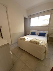 a bedroom with a bed with blue pillows and a window at Hotel Albamar in Mar del Plata