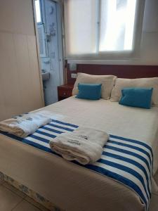 Una cama con toallas azules y blancas. en Hotel Albamar en Mar del Plata