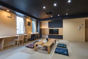 een woonkamer met een tafel en stoelen en een televisie bij Hotel Sugicho in Kyoto