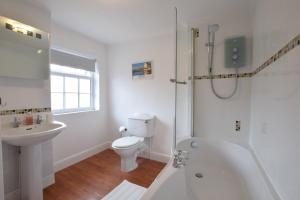 een witte badkamer met een toilet en een wastafel bij 1 Tailors Cottage, Woodbridge in Woodbridge