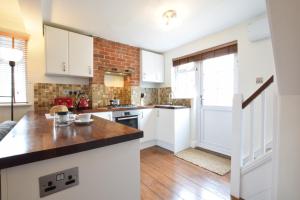 a kitchen with white cabinets and a brick wall at 1 Tailors Cottage, Woodbridge in Woodbridge +15 photos