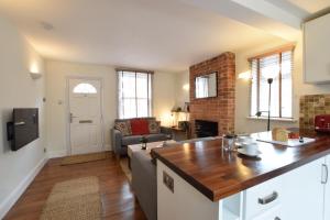 a kitchen and living room with a couch and a table at 1 Tailors Cottage, Woodbridge in Woodbridge