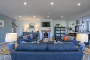 Sea Green Cottage, Walberswick في والبيرسويك: غرفة معيشة مع أرائك زرقاء ومدفأة