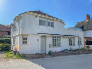 Sea Green Cottage, Walberswick في والبيرسويك: بيت ابيض وباب ازرق على شارع