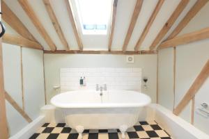 La salle de bains est pourvue d'une baignoire blanche et d'un sol en damier. dans l'établissement Fishpond House, Sotherton, à Sotherton