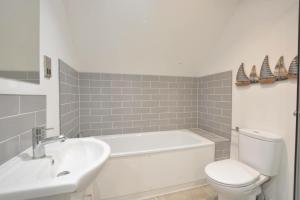 a bathroom with a white tub and a toilet and a sink at Corner Cottage, Thorpeness in Thorpeness