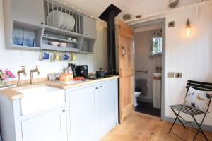 uma cozinha com armários brancos e um lavatório em Shepherds Pightle, Hollesley em Hollesley