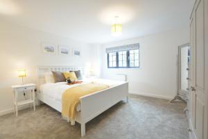 a white bedroom with a bed and a window at Corner Cottage, Thorpeness in Thorpeness