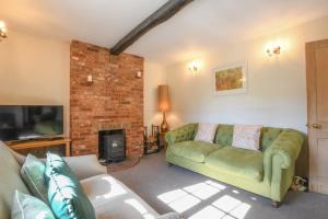 Chapel Cottage, Newbourne في Newbourn: غرفة معيشة مع أريكة خضراء ومدفأة