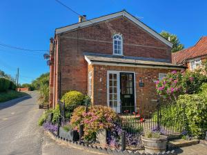 ein Backsteinhaus mit Blumen davor in der Unterkunft Chapel Cottage, Newbourne in Newbourn