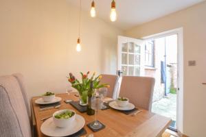 a dining room with a wooden table with flowers on it at Chapel Cottage, Newbourne in Newbourn