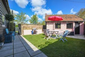 a patio with a table with a red umbrella at Pink Cottage, Stradbroke in Stradbroke