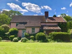 una casa con un césped verde delante de ella en Rectory Farm Cottage, Rougham, en Rushbrooke
