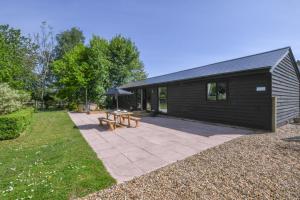 a black house with a picnic table and a patio at The Piglets in Woodbridge