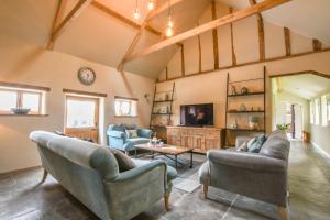a living room with two couches and a tv at Halcyon Barn, Wissett in Wissett