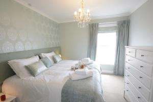 een slaapkamer met een wit bed en een kroonluchter bij St Marys View, Southwold in Southwold