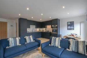 a living room with two blue couches and a kitchen at Salt Marsh House, Southwold in Southwold