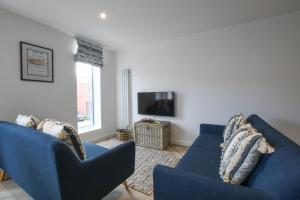 a living room with two blue couches and a tv at Salt Marsh House, Southwold in Southwold