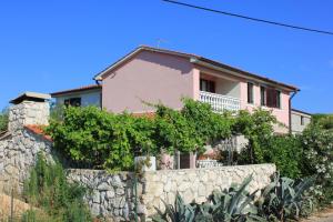a pink house behind a stone wall at Apartments with a parking space Punta kriza, Cres - 383 in Punta Križa