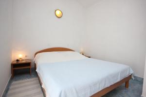 a bedroom with a large white bed and a table at Apartments with a parking space Punta kriza, Cres - 383 in Punta Križa