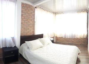 1 dormitorio con cama blanca y pared de ladrillo en CASA HOTEL VILLA Lorena, en San Agustín