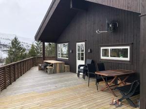 uma casa com um deque de madeira com uma mesa e cadeiras em Holiday home Skare em Skare