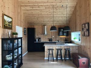 a kitchen with wooden walls and a island with bar stools at Holiday home Skare in Skare