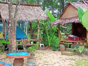 a garden with a hut with a table and a bench at Wassana Camp & Khai Jungle Experience Centour in Ban Kraison