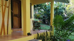 una casa gialla con una sedia su un portico di Mira Olas Cabins a Pavones