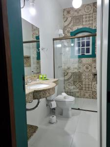 La salle de bains est pourvue de toilettes, d'un lavabo et d'une douche. dans l'établissement Pousada Candelabro, à Tiradentes