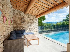 a patio with a couch and a table next to a swimming pool at Bastide with pool and panoramic views in Ménerbes