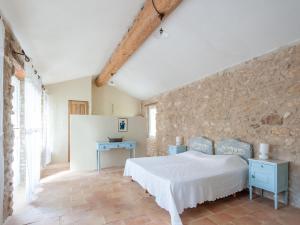 a bedroom with a white bed and a stone wall at Bastide with pool and panoramic views in Ménerbes