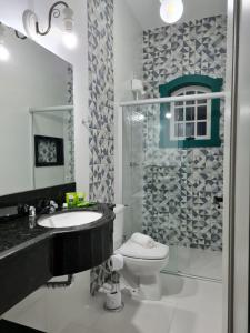 uma casa de banho com um WC, um lavatório e um chuveiro em Pousada Candelabro em Tiradentes