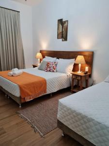 a bedroom with two beds and a table with lamps at Pousada Candelabro in Tiradentes