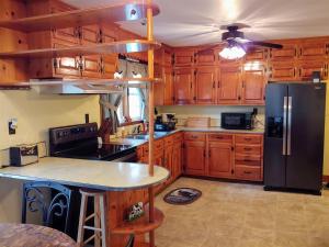 a kitchen with wooden cabinets and a black refrigerator at B And A Lake Cottage in Luray