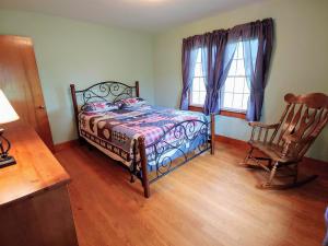 a bedroom with a bed and a chair and two windows at B And A Lake Cottage in Luray