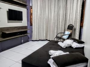 ein Schlafzimmer mit einem schwarzen Bett und einem Stuhl in der Unterkunft Casa de Temporada no Centro de Pedra Azul in Pedra Azul