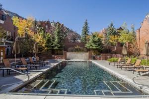 a swimming pool with chairs and a swimming poolvisor at Aspen Mountain Residences, 2 Bedroom Luxury Residence Club Condo in Aspen